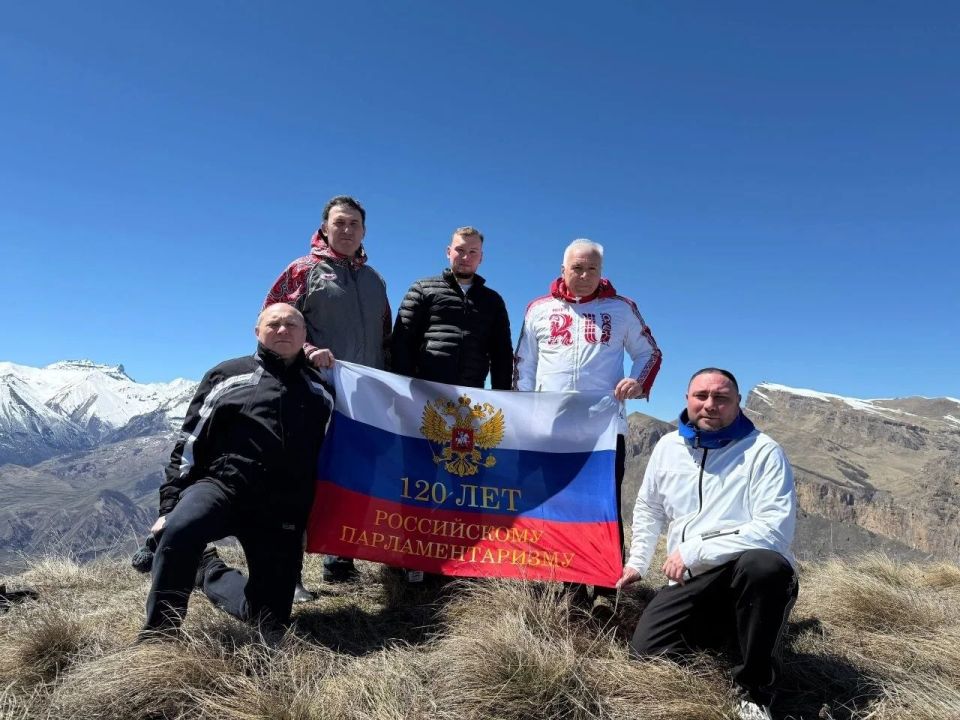 На одной из вершин Скалистого хребта в Чегемском ущелье законодатели развернули флаг с надписью "120 лет российскому парламентаризму"
